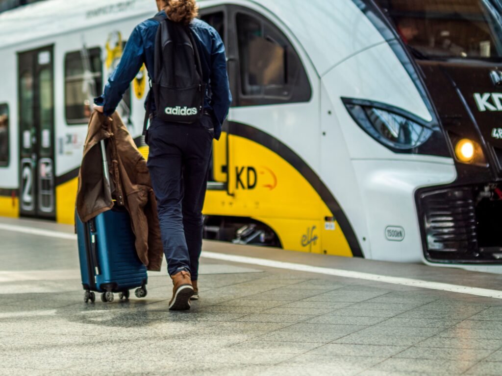 Person with suitcase preparing to board a train at a station.