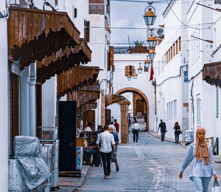 Scenic view of a Moroccan alley with traditional white buildings and street life. Ideal for travel and culture themes.