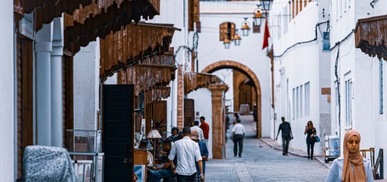 Scenic view of a Moroccan alley with traditional white buildings and street life. Ideal for travel and culture themes.